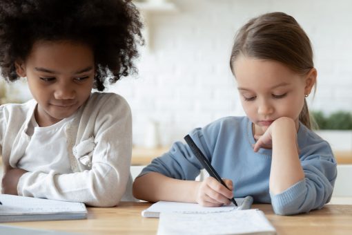 två flickor i skolåldern vid ett skrivbord