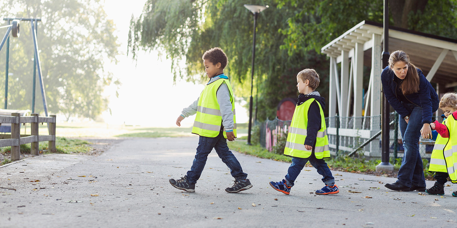 Pre-school chidren in yellow vests crossing street.