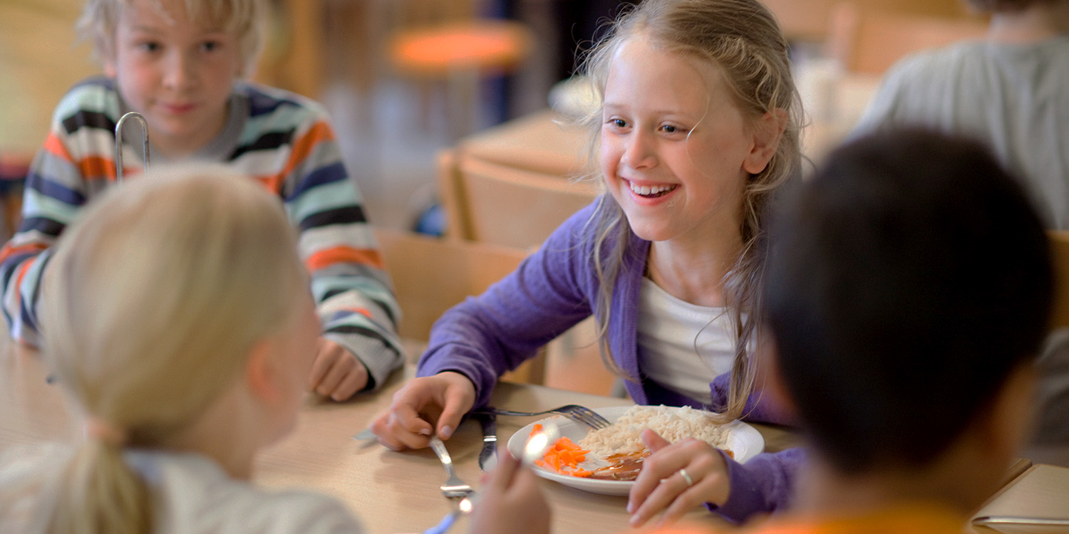 Children in a school dining hall eating lunch.