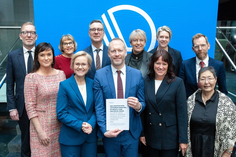 Bilde av 11 helse- og sosialministre med et papir foran seg og Nordisk råds logo i bakgrunnen. 