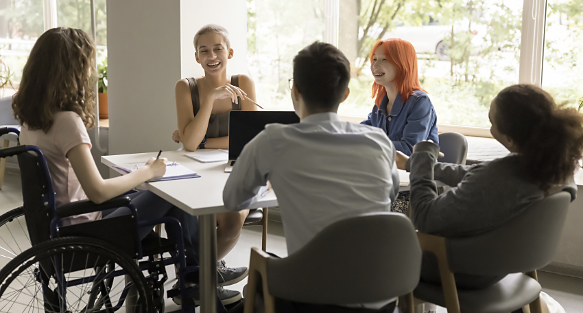 En gruppe på 5 unge personer som sitter rundt et samarbeidsbord.