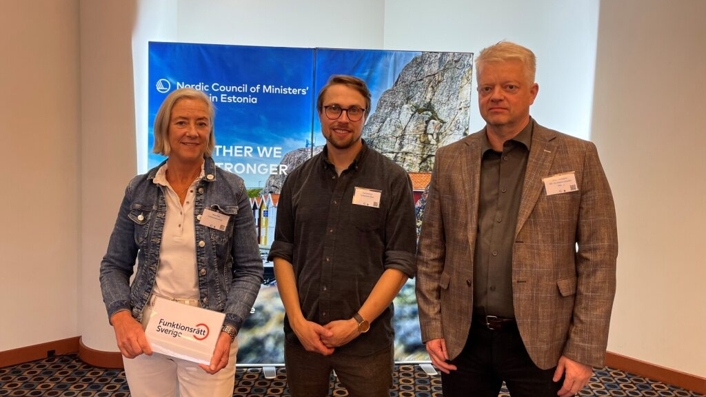 En kvinne og to menn stirrer inn i kamera. De deltar på en konferanse og har navneskilt på seg.  