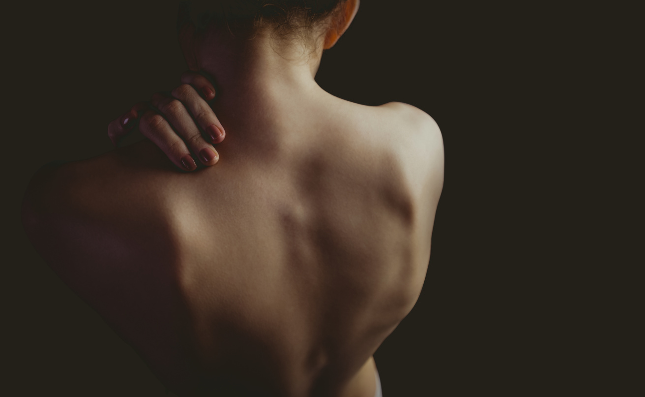 Nude woman with a shoulder injury on black background