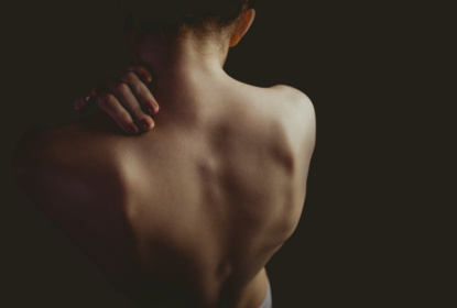 Nude woman with a shoulder injury on black background