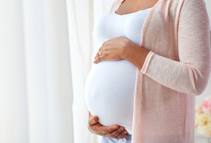 Gravid person håller händerna på magen.