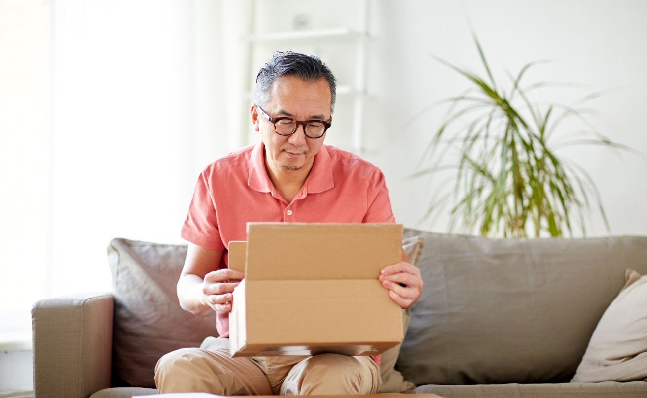 Man sitter i en soffa och öppnar ett paket