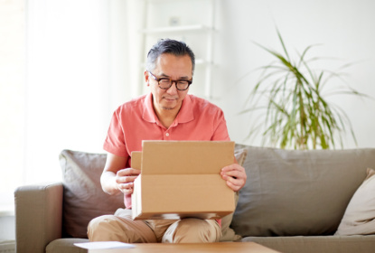 Man sitter i en soffa och öppnar ett paket