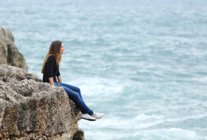 11328193-casual-woman-sitting-in-a-cliff-watching-the-sea