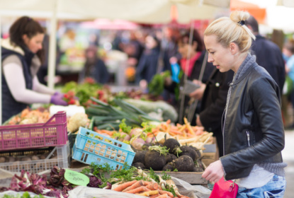 Woman buying vegetable at local food market.