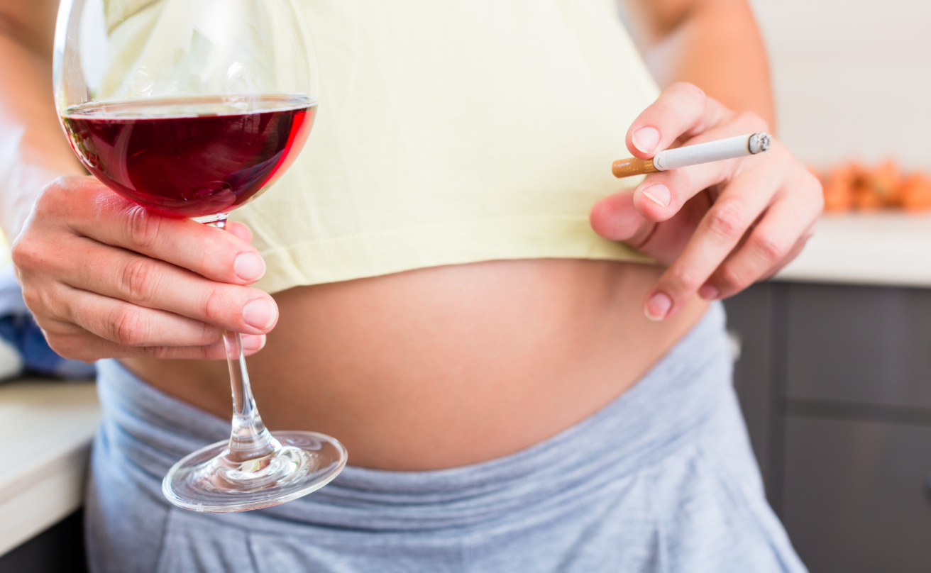 Pregnant woman with glass of wine and cigarrette in hand