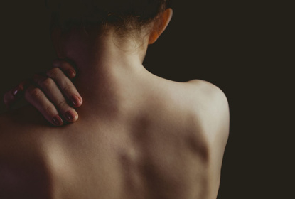 Nude woman with a shoulder injury on black background
