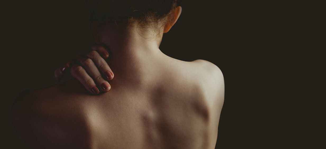 Nude woman with a shoulder injury on black background