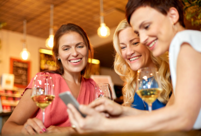 women with smartphone at wine bar or restaurant
