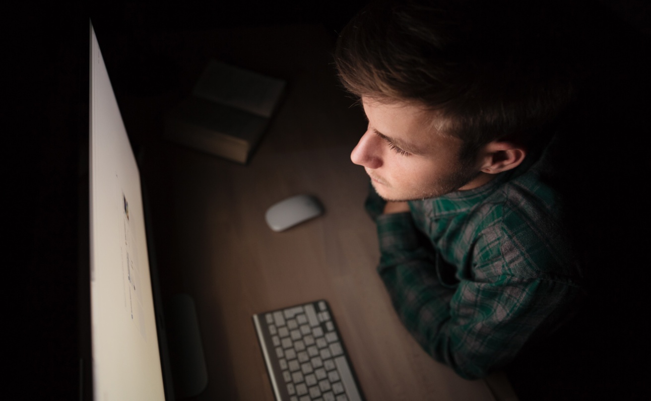 Man sitting and working with computer in the dark room