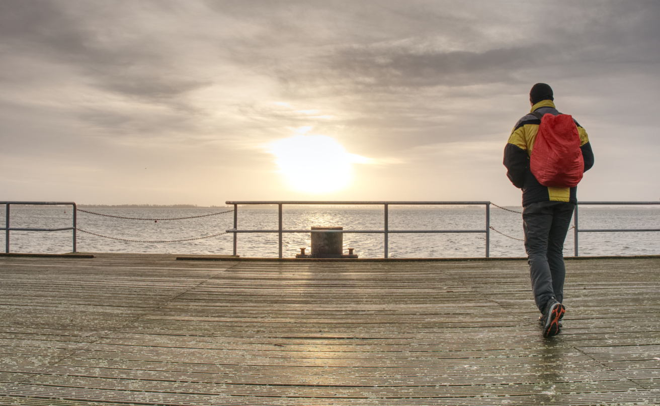 Traveler with back pack at ferry port, pier in touristic resort.