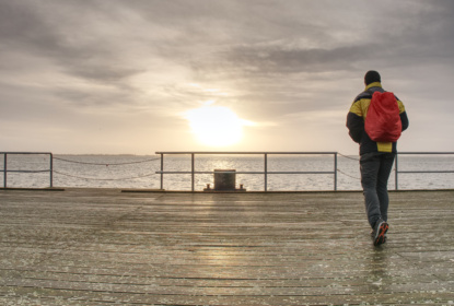Traveler with back pack at ferry port, pier in touristic resort.