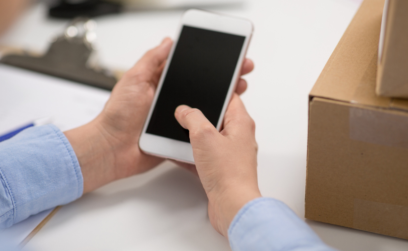 hands with smartphone and parcels at post office