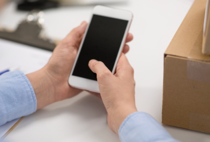 hands with smartphone and parcels at post office
