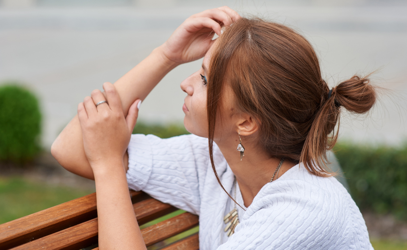 Beautiful young woman sits on a bench in the summer park