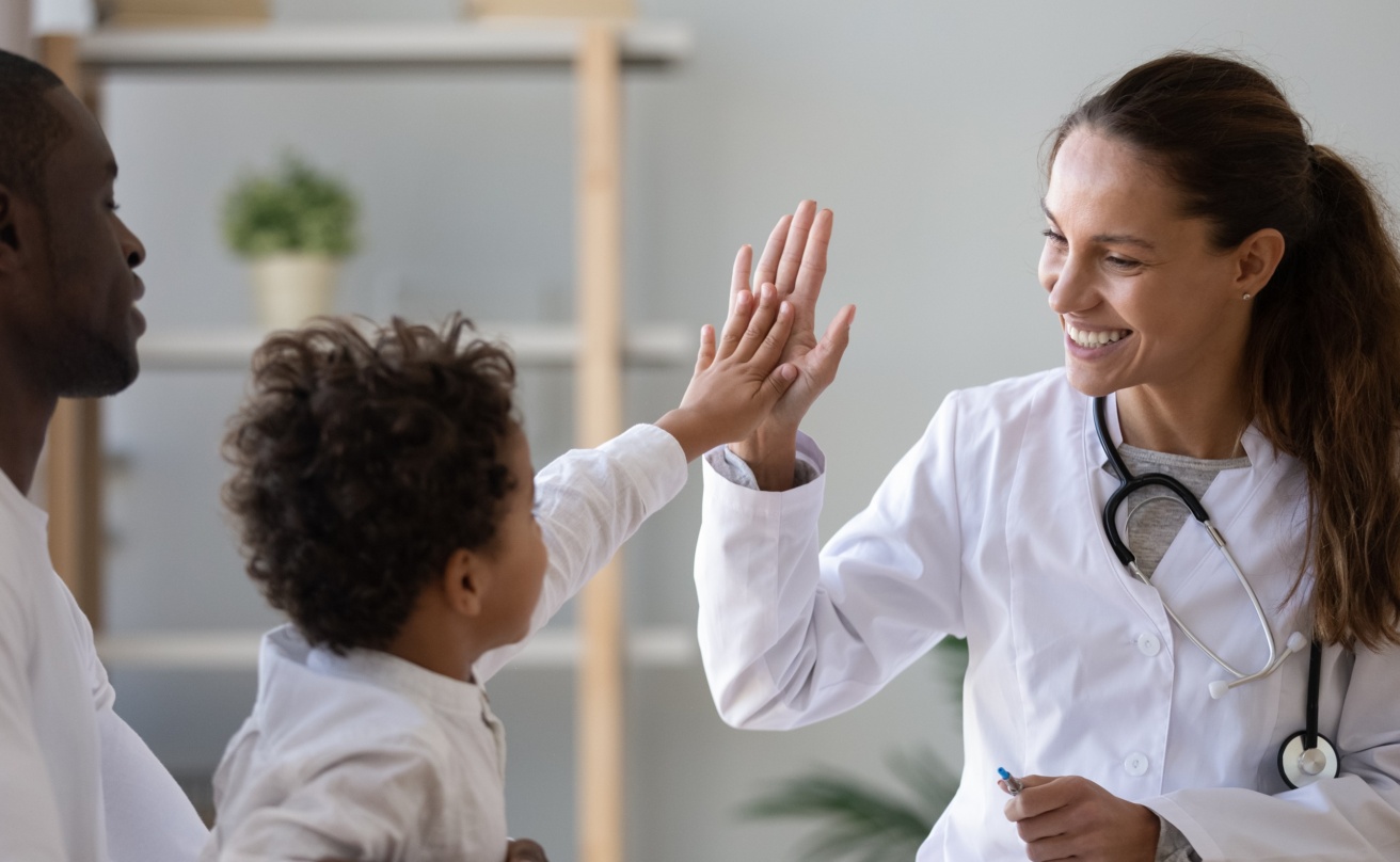 Smiling female doctor give high five to a child.