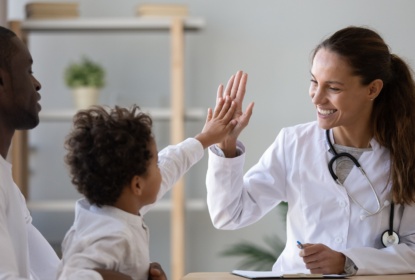 Smiling female doctor give high five to a child.