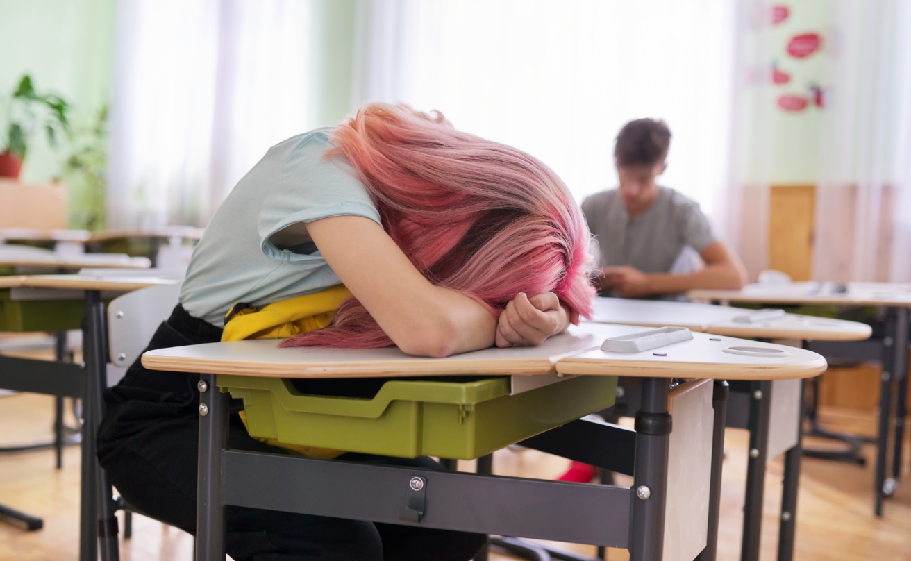 Tired girl teenage student asleep on her desk