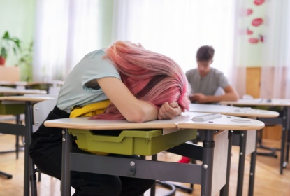 Tired girl teenage student asleep on her desk