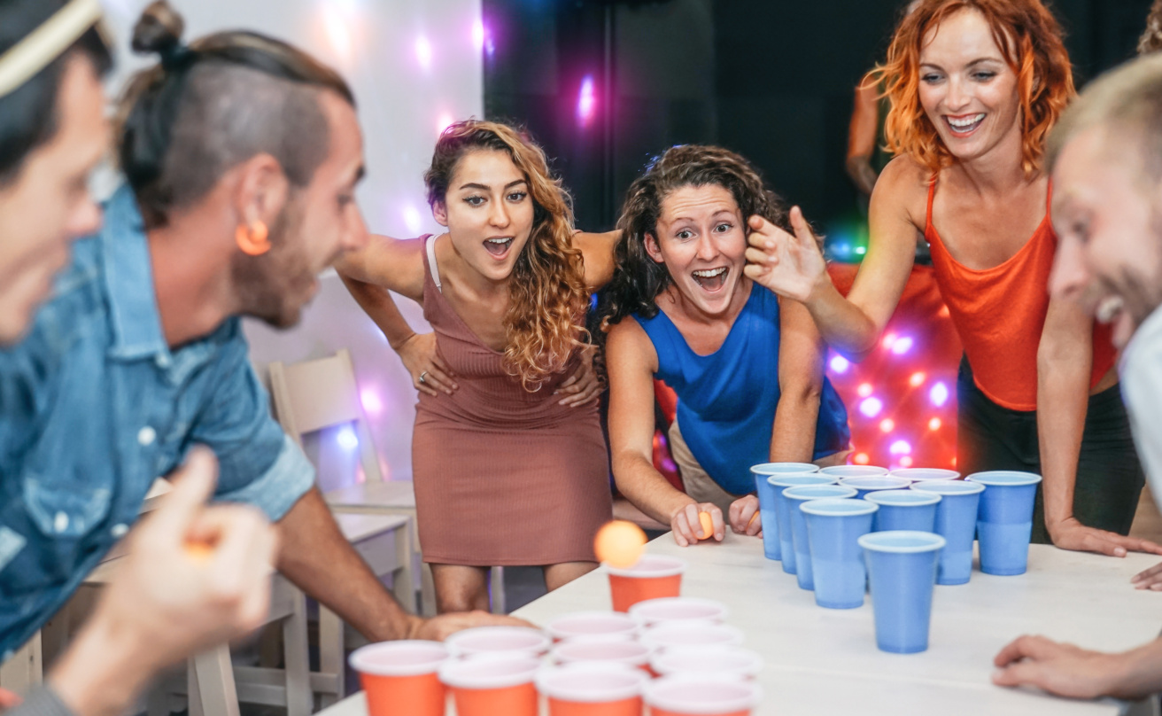 Group of happy friends playing beer pong