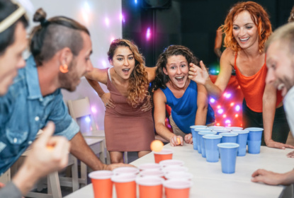 Group of happy friends playing beer pong
