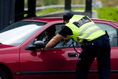 Tulltjänsteman står lutad över personbil och pratar med föraren.