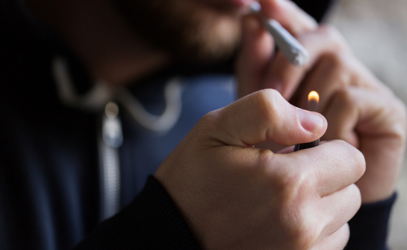 En man tänder en cannabisjoint.