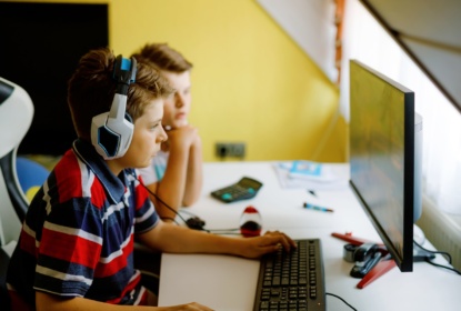 Two boys playing computer games on desktop pc