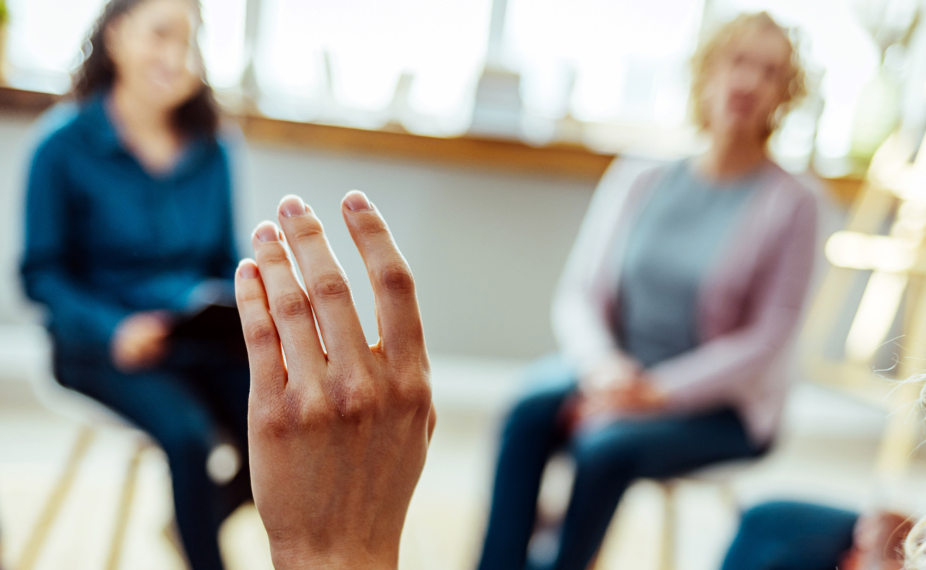 Uppräckt hand framför en grupp av människor