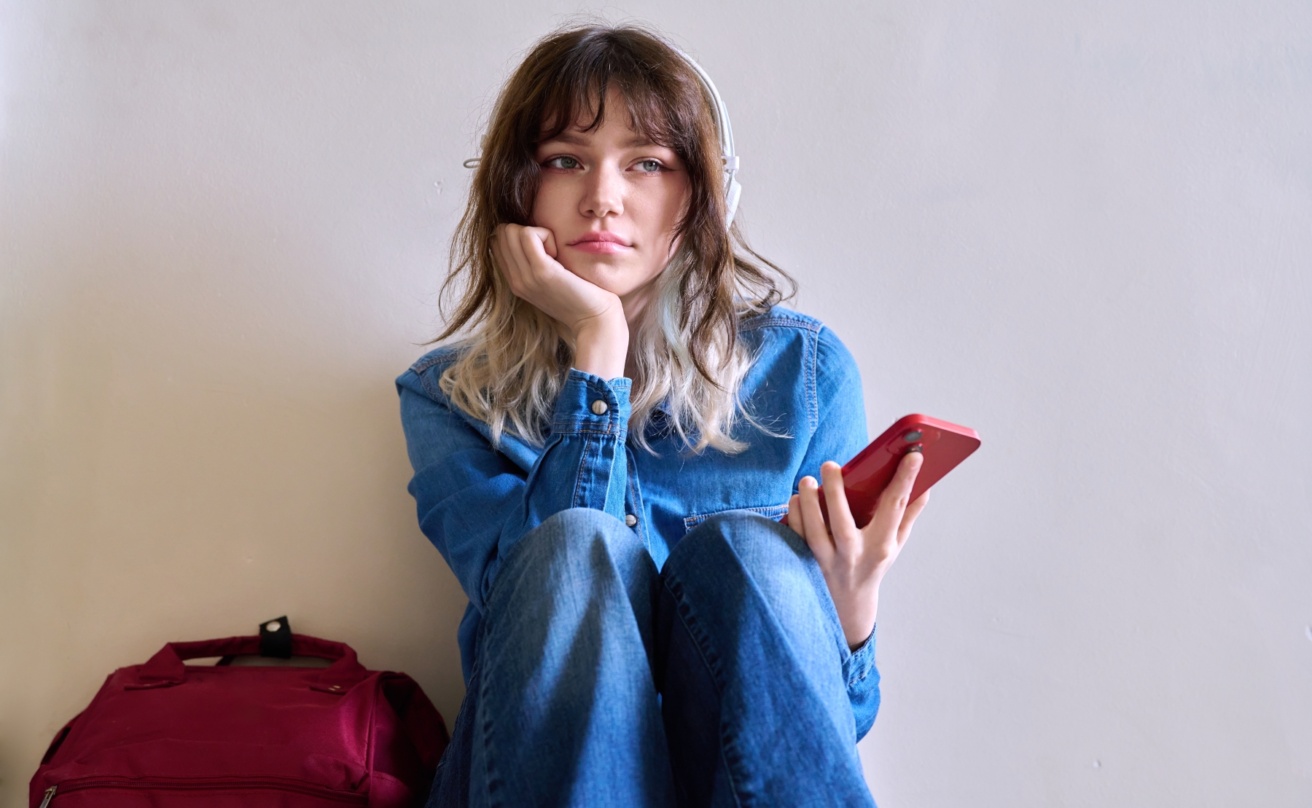 57036179-sad-young-female-student-with-backpack-smartphone
