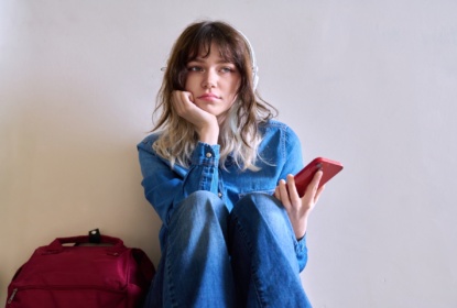 57036179-sad-young-female-student-with-backpack-smartphone
