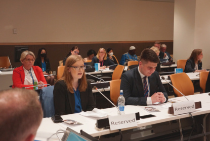 A woman and a man sitting at a conference table, the woman speaking