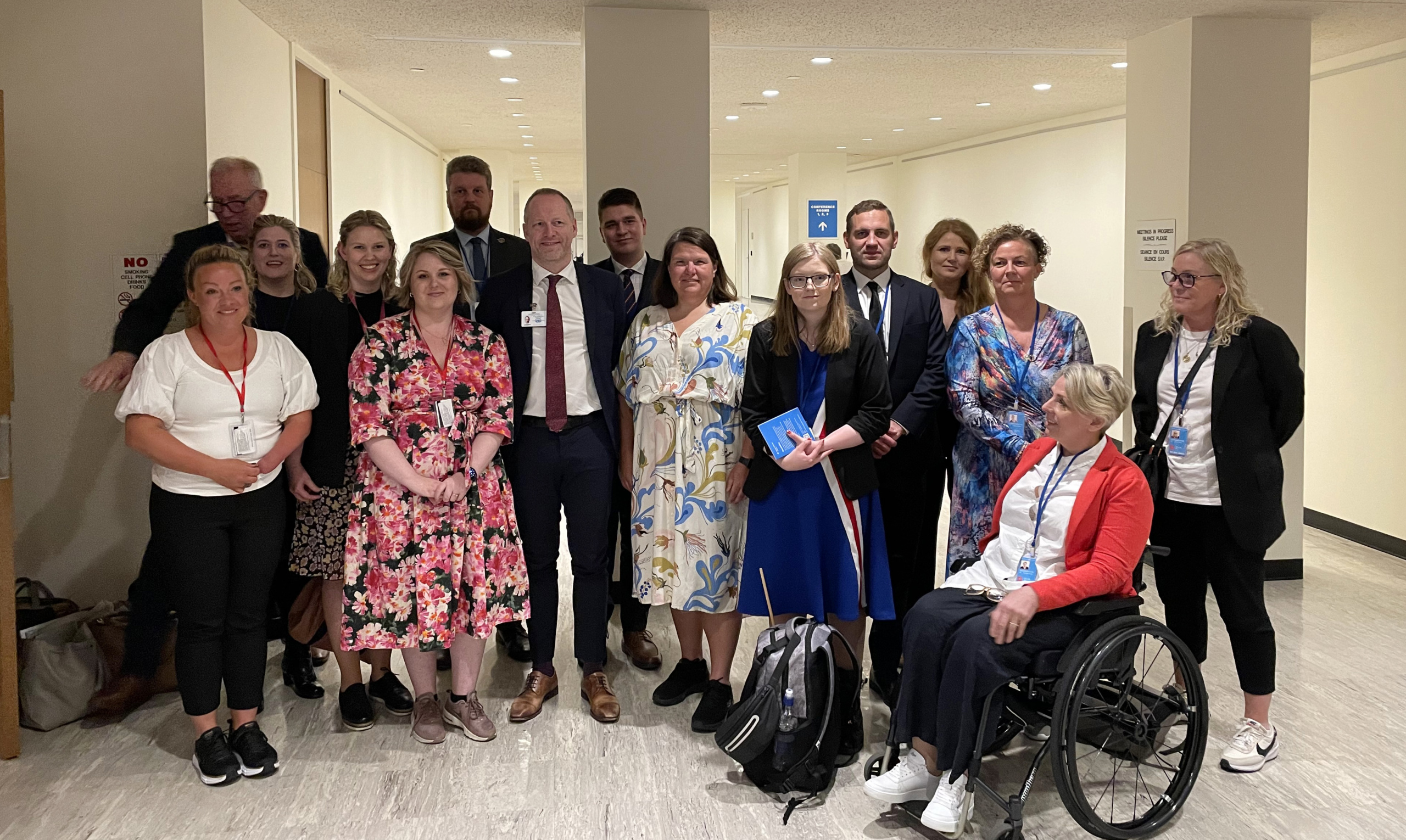 Group picture of 15 people standing and sitting in a room.