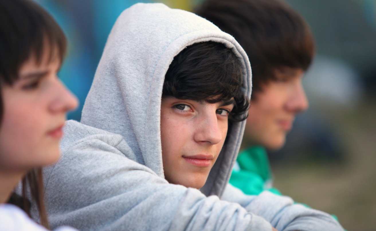 Three teenagers sitting together, one looks into the camera