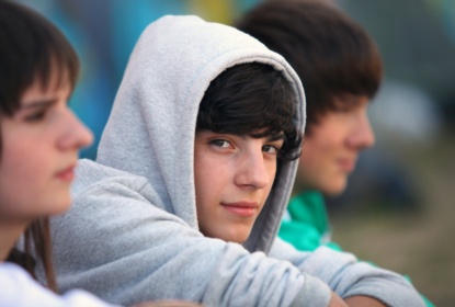 Three teenagers sitting together, one looks into the camera