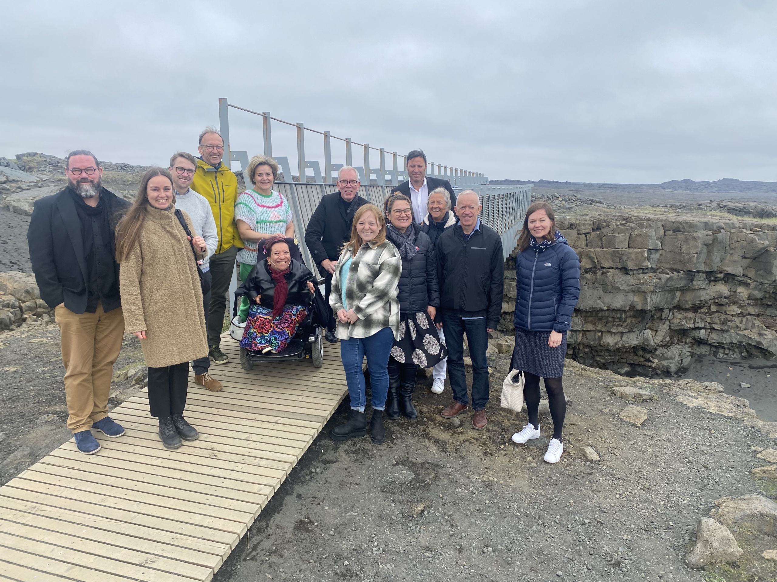 Group picture outside in front of a bridge over a gap on a lava field.