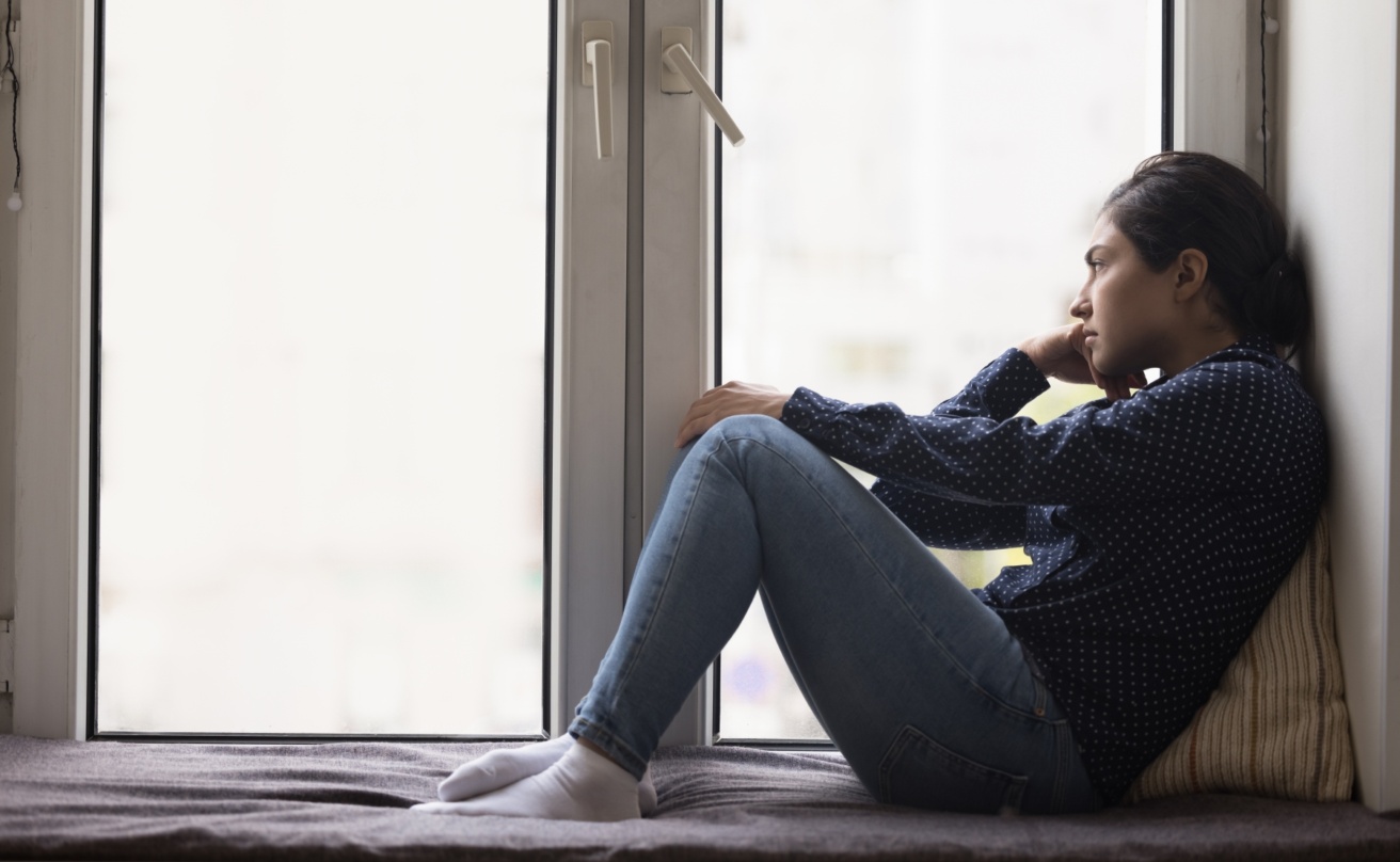 59271471-unhappy-lonely-young-indian-woman-sitting-on-windowsill