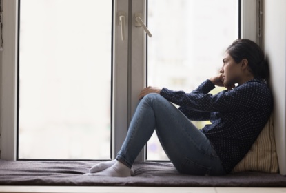 59271471-unhappy-lonely-young-indian-woman-sitting-on-windowsill