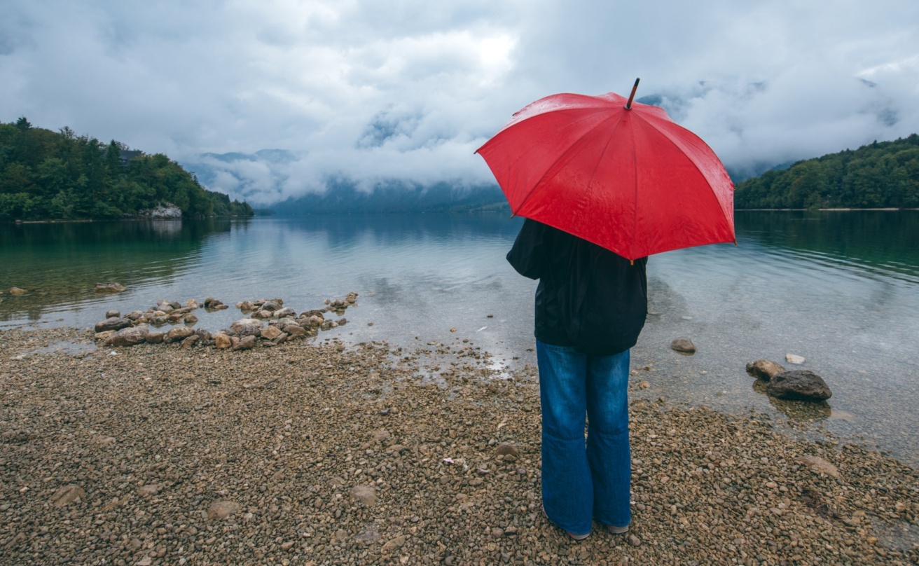 Woman with red umbrella contemplates in rain