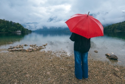 Woman with red umbrella contemplates in rain