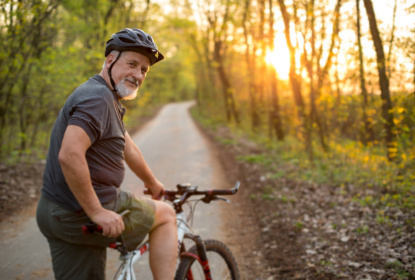 Äldre man cyklar i naturen.