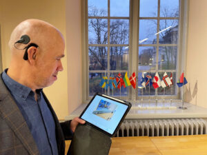 Man with ipad showing the same flags as in the background and a text description
