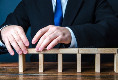 52177077-a-man-building-a-bridge-of-domino-blocks-strategy