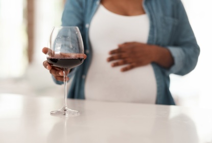 Pregnant women reaching out for a glass of red wine