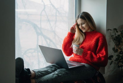 Woman with red shirt looking at her laptop while smiling