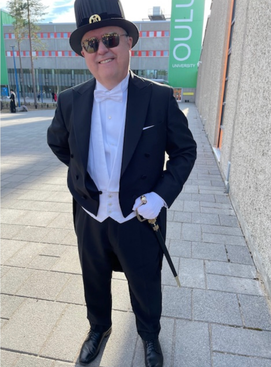 Russ palmer står i doktorhatt framför Oulo univeristet